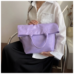 Primer plano de un bolso tote violeta de piel sintética suave con asas dobles