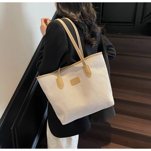 Detail of the large canvas tote bag showing beige fabric and coffee leather straps