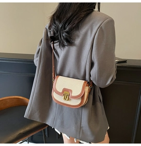 Detail of canvas saddle bag with brown leather trim and retro metal buckle on a model