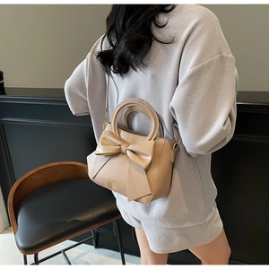 Detailed view of apricot shoulder bag featuring a 3D bow design and textured PU leather