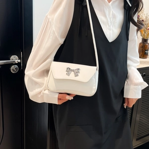 White minimalist square shoulder bag with silver bow accent on a fashion model