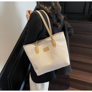 Detailed view of canvas tote bag with brown leather handles on wooden stairs