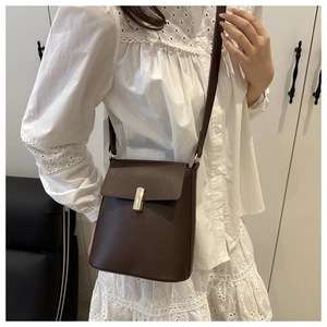 Détail d'un sac bandoulière marron foncé structuré avec fermoir magnétique doré