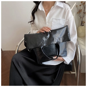 Bolso tote extragrande de piel sintética negra mostrado por una modelo en un interior