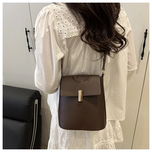 Détail du sac bandoulière en cuir marron foncé avec boucle en métal doré minimaliste