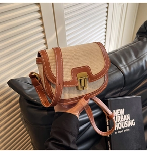 Detail of saddle bag with beige woven canvas, brown leather trim and gold metal clasp