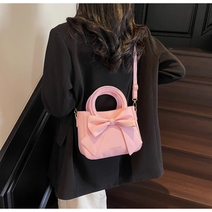 Macro detail of a pink bow square bag featuring matte PU leather and adjustable strap