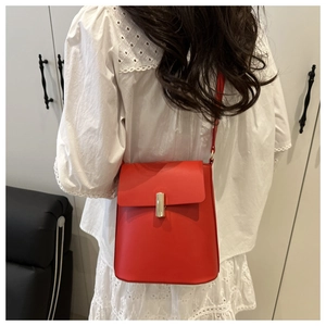 Vue détaillée du sac bandoulière en cuir rouge avec boucle dorée sur un mannequin
