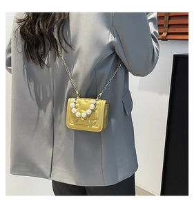 Detail of gold crossbody bag with heart embossed pattern and pearl bead handle
