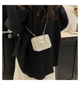 Close-up of heart-embossed white mini bag with large pearl handle and gold chain strap