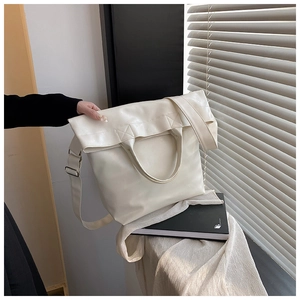 Detalle de un bolso tote grande blanco crema con diseño plisado y correa de hombro ancha