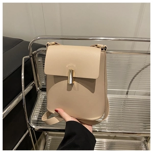 Détail d'un sac à bandoulière en cuir beige avec serrure cylindrique dorée élégante