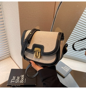 Detail of vintage saddle bag featuring canvas and black leather with bronze buckle