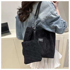 Detail of black corduroy tote bag with chain strap and matching small pouch