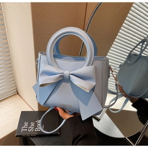 Detailed view of light blue square bag featuring a large decorative 3D bow and ring handle