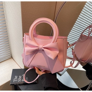 Close-up of pink PU leather handbag with large bow and gold Fashion & Bags logo