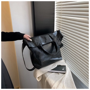 Primer plano de bolso tote de cuero negro brillante con apertura plegada elegante