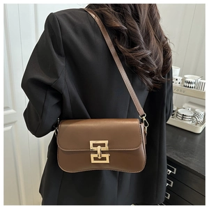 Rear view of a vintage brown leather bag worn over a black blazer with gold buckle detail