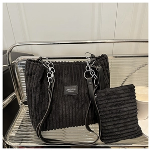Detail of black corduroy tote bag with metallic chain strap and matching small pouch