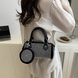 Sac cylindre noir chic avec clous argentés et bandoulière chaîne en décor moderne