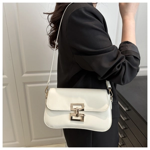 Detail of white PU leather crossbody bag with gold geometric buckle on a black blazer