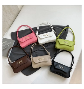 Multiple colors of bow-knot baguette bags displayed on a grey textured fabric background