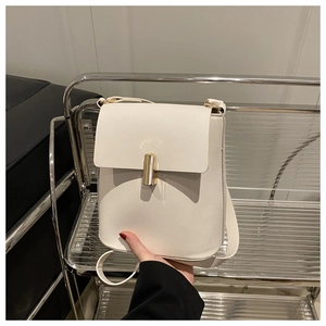 Détail d'un sac à bandoulière carré blanc crème doté d'un fermoir doré cylindrique