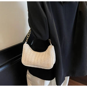 Detail of cream woven shoulder bag with white leather trim and gold chain strap on model