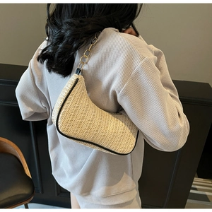 Close-up of beige woven texture and gold chain strap on stylish shoulder bag