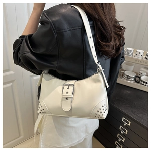 Détail d'un sac sous le bras en cuir blanc avec rivets argentés et boucle métallique