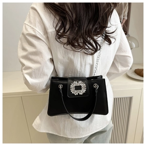 Détail du sac bandoulière en cuir noir avec boucle en cristal et chaîne argentée