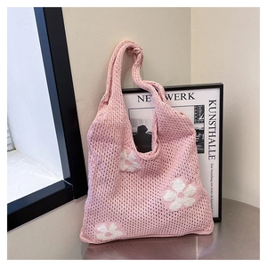 Close-up of pink crochet knit tote bag featuring white daisy flowers and mesh texture