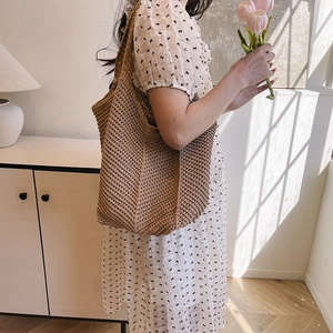 Deep brown hand-crocheted woven tote bag worn by model in a minimalist setting