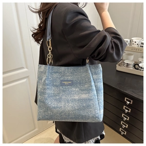 Detail of blue denim tote bag featuring glitter texture and golden chain strap for women
