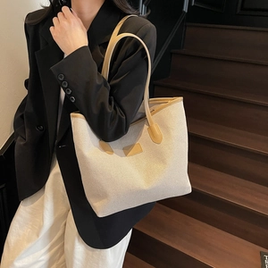 Minimalist canvas tote bag with brown leather trim carried by a model on stairs