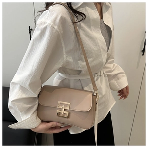 Detail of light brown crossbody bag with gold buckle and smooth faux leather finish