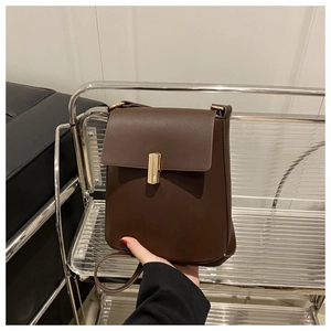 Détail d'un sac bandoulière en cuir marron foncé avec boucle rectangulaire dorée