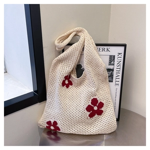 Close-up of beige crochet tote bag featuring intricate red knitted floral patterns