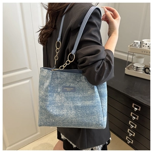 Detail of blue denim tote bag with sequin texture and gold metal chain strap