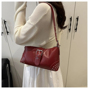 Détail d'un sac à main vintage en cuir rouge foncé avec boucle argentée et rivets