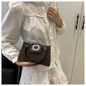 Brown retro square bag with large rhinestone buckle and metal handle carried by model