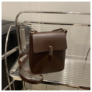 Détail du sac en cuir marron foncé montrant l'élégante boucle en métal doré et texture