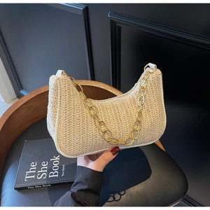 Detail of beige straw hobo bag with woven chevron pattern and gold chain strap