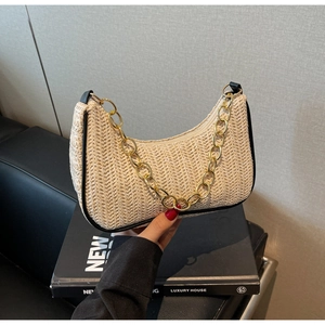 Detail of woven straw underarm bag with black leather trim and golden chain strap