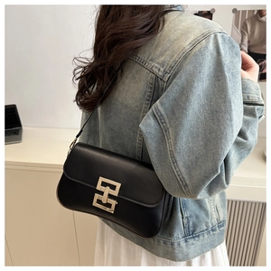 Detail of a chic black leather crossbody bag featuring a designer gold interlocking buckle