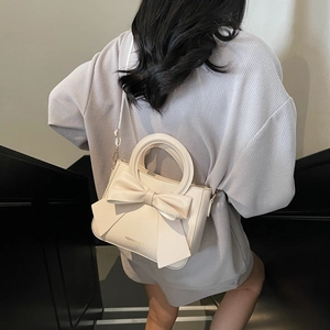 Fashionable cream square crossbody bag with large bow detail and elegant handle
