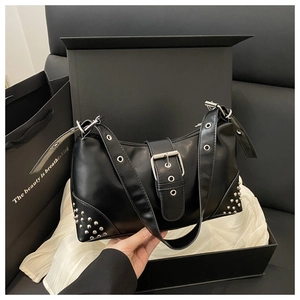 Détail du sac croissant noir brillant avec clous argentés et boucle sur coffret cadeau