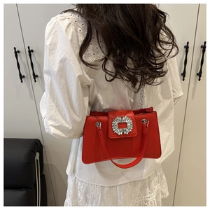 Detailed view of the red leather bag featuring a large square crystal buckle and silver hardware