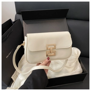 Close-up of cream square handbag with gold metal clasp in elegant gift box packaging