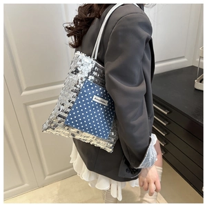 Detail of silver sequin tote bag featuring a blue denim pocket and white slim shoulder straps